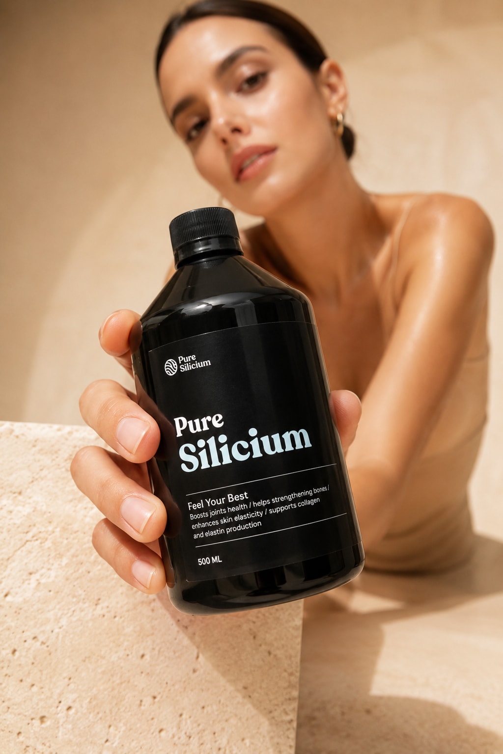 A model holds a 500ml Pure Silicium bottle in warm sandstone light